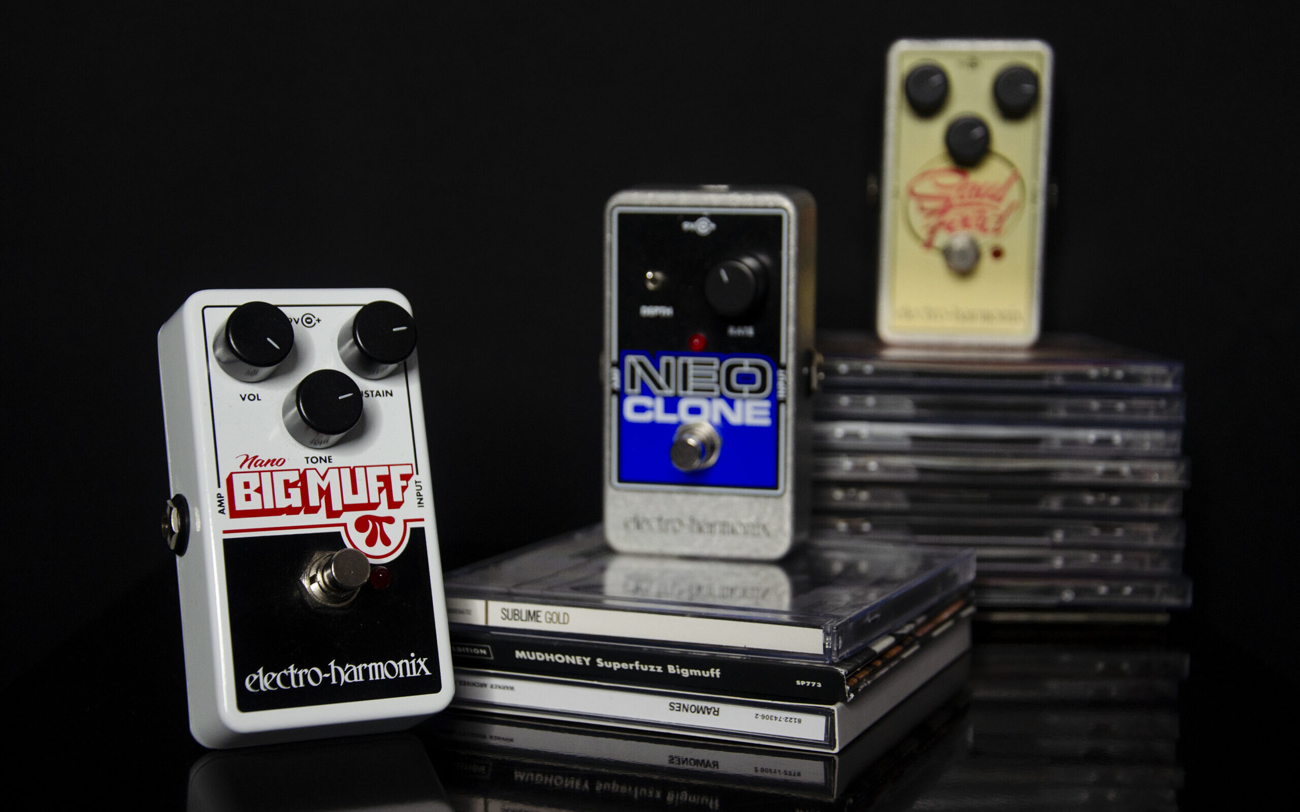 Three guitar pedals on black background sitting on CD cases