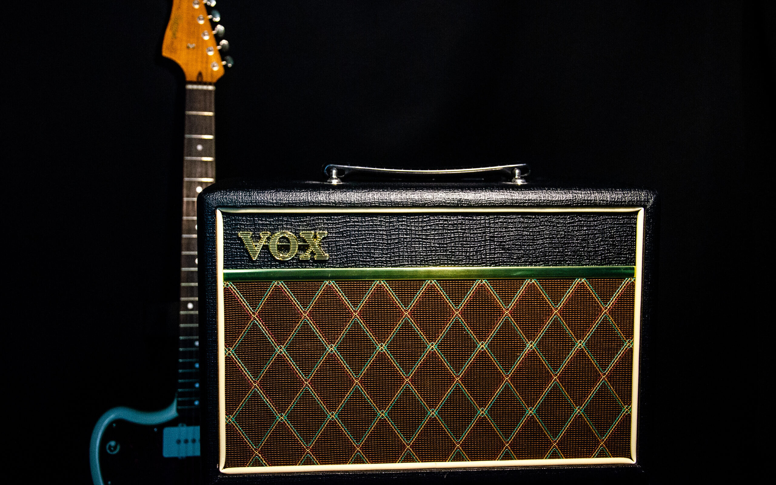 Guitar amp on black background next to guitar